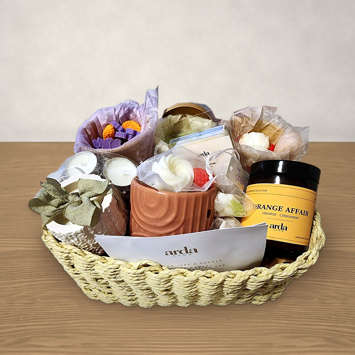 Cesta regalo personalizada mediana Arda Home con vela Orange Affair y wax melts sobre mesa de madera
